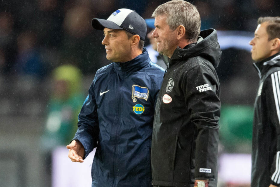 Düsseldorfs Trainer Friedhelm Funkel (M.) und Herthas Trainer Ante Covic (l.) beobachten den Schiedsrichter vor der Elfmeter-Entscheidung für Düsseldorf.