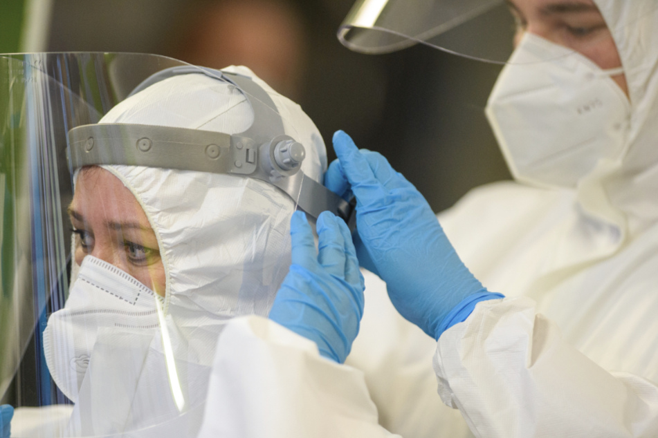 Zwei Mitarbeiter eines Klinikum legen sich Schutzkleidung an. Bei einem Ehepaar aus Stuttgart wurde nun erstmals die südafrikanische Coronavirus-Variante nachgewiesen. (Symbolbild)