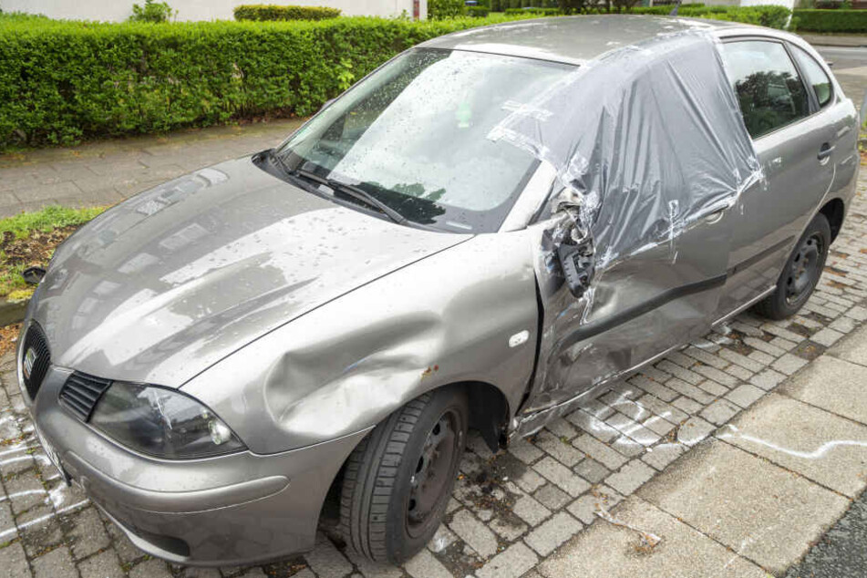 Ein durch den Unfall beschädigtes geparktes Fahrzeug steht am Straßenrand.