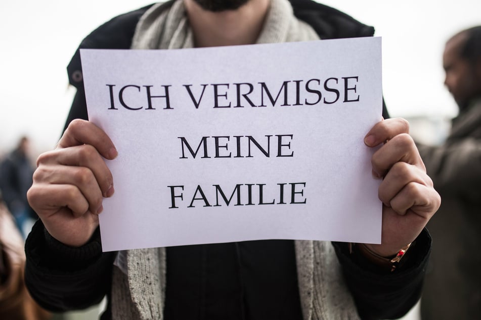 Ein Mitglied des Flüchtlingsrats hält ein Schild mit der Aufschrift "Ich vermisse meine Familie" in den Händen.