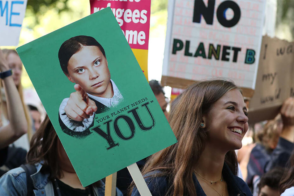 Zahlreiche Menschen hören bei einer Demonstration den Sprechern des "UK Student Climate Network" zu und marschieren mit Protestplakaten.