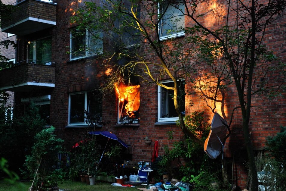 Die Flammen schlagen aus dem Fenster gegen das Mehrfamilienhaus.