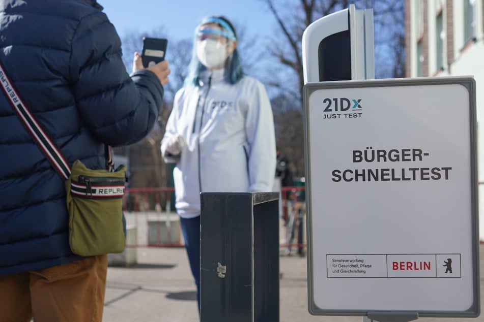Eine Mitarbeiterin der Betreiber-Firma 21Dx GmbH und ein Bürger stehen vor einem Corona-Schnelltestzentrum in der Lehrter Straße. Seit Montag ermöglicht die Bundesregierung allen Bundesbürgern kostenfreie Corona-Tests.