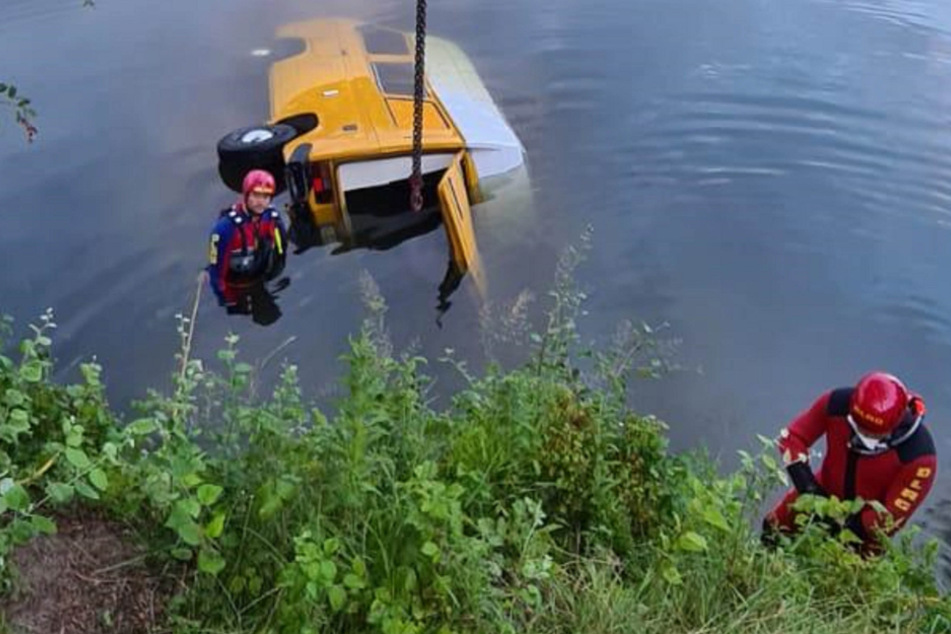 DLRG-Taucher befinden sich im Wasser bei dem Campingbus, an dem ein Seil befestigt ist.