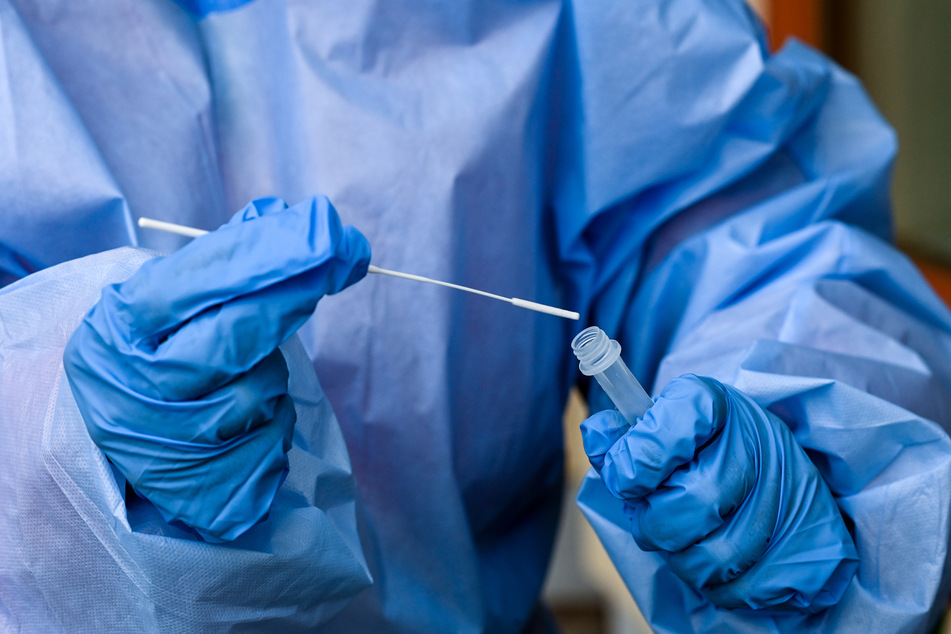 Eine Krankenschwester steckt während einer Corona-Testung ein Teststäbchen in die Flüssigkeit eines Schnelltests. In Hamburg sind vier weitere Infektionen mit der Omikron-Variante bestätigt worden. (Symbolfoto)