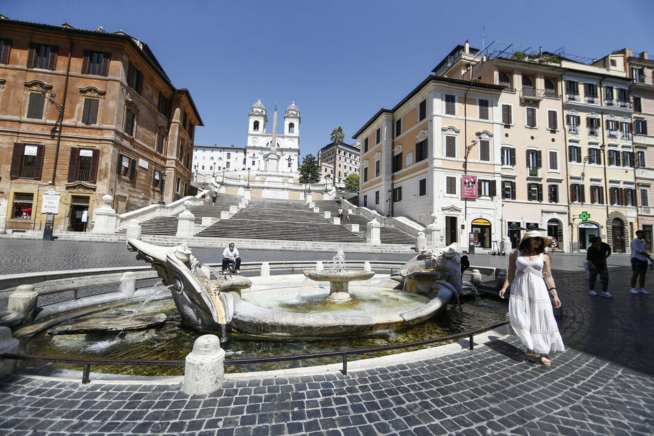 Rom: Einzelne Touristen stehen am Brunnen "Fontana della Barcaccia" vor der Spanischen Treppe, einem der Touristen-Hotspots. Die Zahl der ausländischen Touristen in Italiens Hauptstadt ist wegen der Corona-Pandemie extrem niedrig.