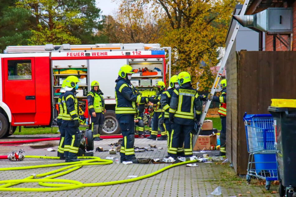 Einsatzkräfte der Feuerwehr stehen vor dem Imbiss in Wandlitz (Barnim).