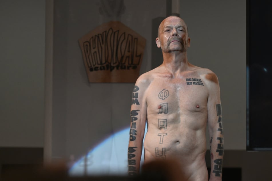 Flatz, Künstler aus Österreich, steht nackt auf einer Bühne in der Pinakothek der Moderne.