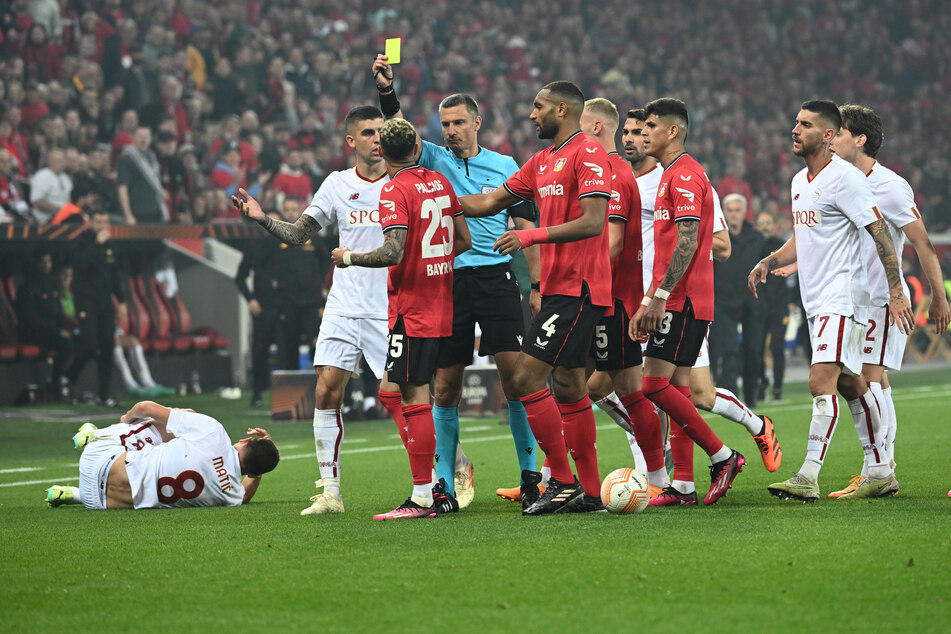 Schiedsrichter Slavko Vincic (43) zeigt Leverkusens Exequiel Palacios (24, Nr. 25) nach einem Foul an Roms Nemanja Matic (34, liegend) die gelbe Karte.