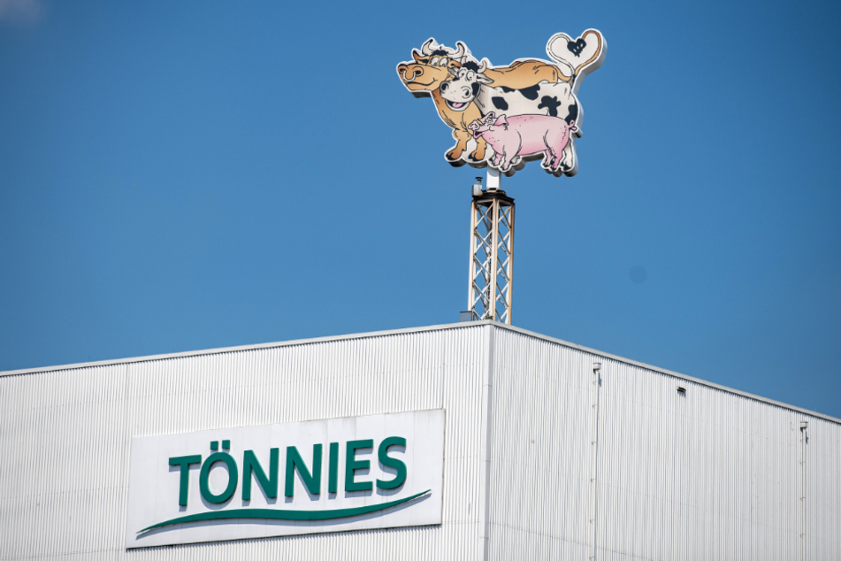 Auf dem Dach eines Gebäudes auf dem Werksgelände steht das Logo der Firma Tönnies in Form von zwei Kühen und einem Schwein.