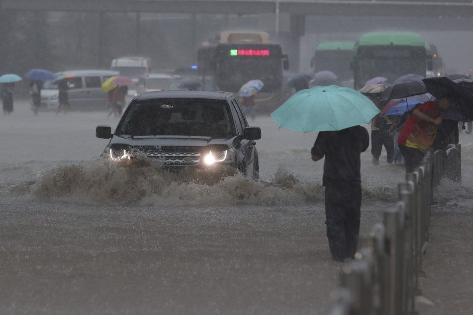 Ein Auto fährt in der zentralchinesischen Provinz Henan über eine überflutete Straße.