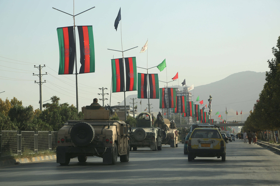 Afghan army vehicles drive down a road in Kabul as the city is taken over by the Taliban.