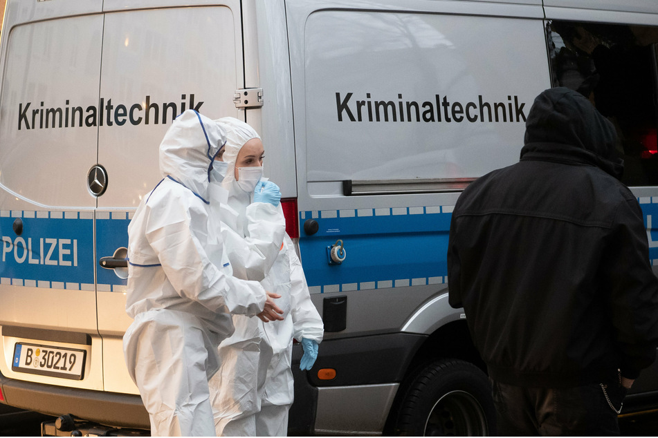 Kriminaltechnikerinnen stehen an einem Einsatzfahrzeug vor einem Wohnhaus in der Mahlower Straße in Berlin-Neukölln.