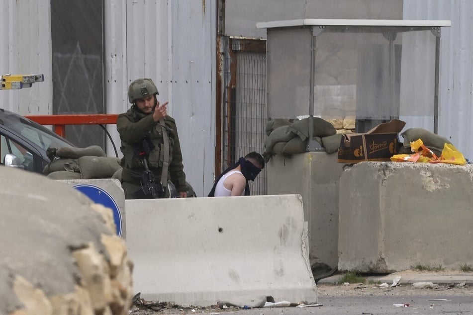 Israeli troops detain a Palestinian man at a checkpoint and close an entrance to the occupied West Bank city of Hebron on January 22, 2025.