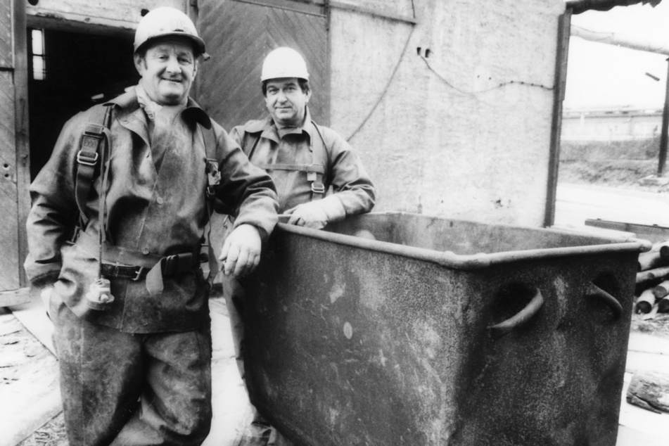 Zwei Bergmänner stehen 1990 an einem Förderwagen, mit dem das Uranerz aus dem Wismut-Schacht Dresden-Gittersee gefördert wurde.
