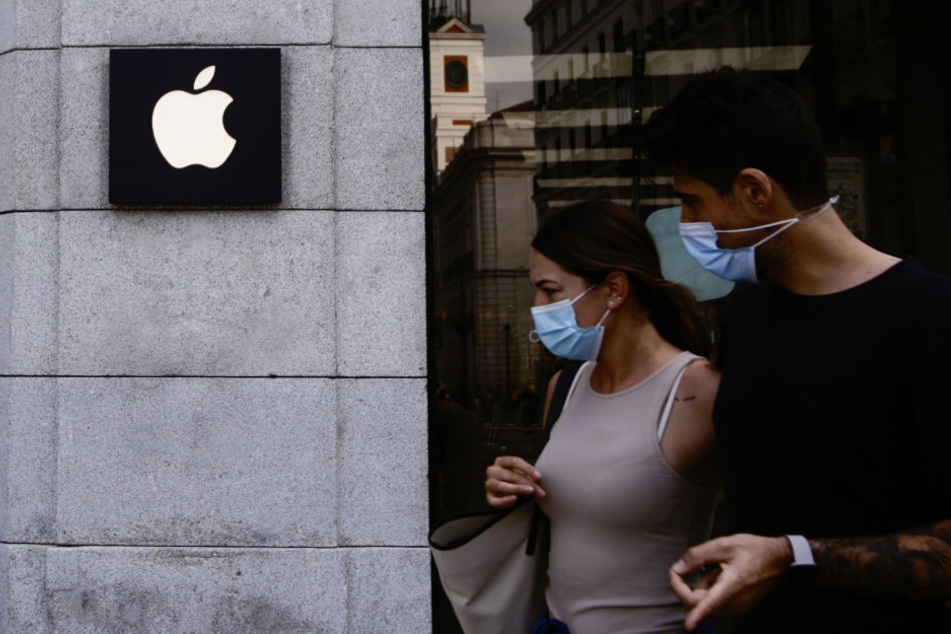 Zwei Personen mit Mundschutz gehen vor einem Apple-Laden in der Innenstadt von Madrid vorbei.