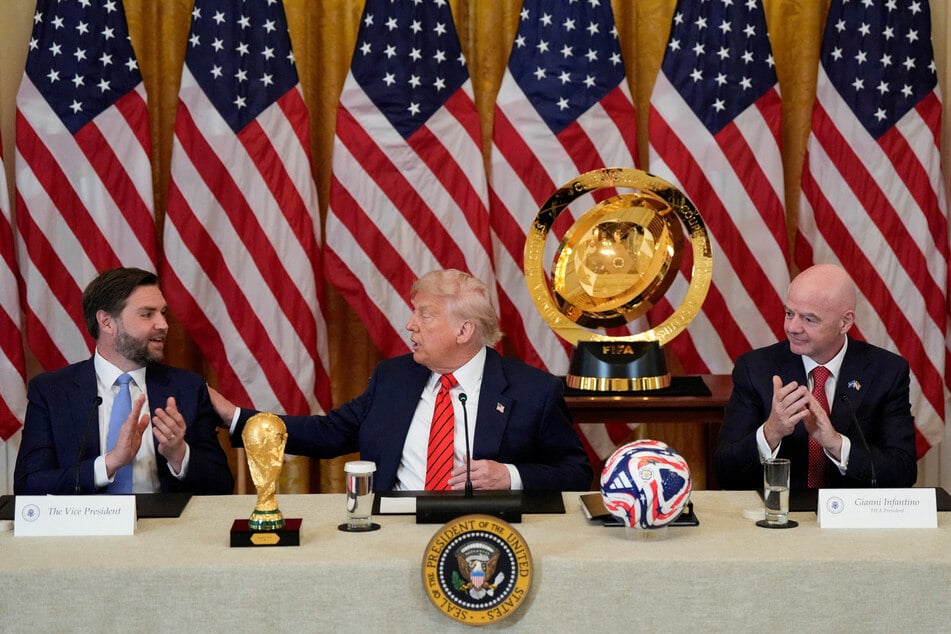 President Donald Trump (c.) gestures to Vice President JD Vance (l.) as he sits alongside FIFA president Gianni Infantino during a FIFA Task Force meeting at the White House.