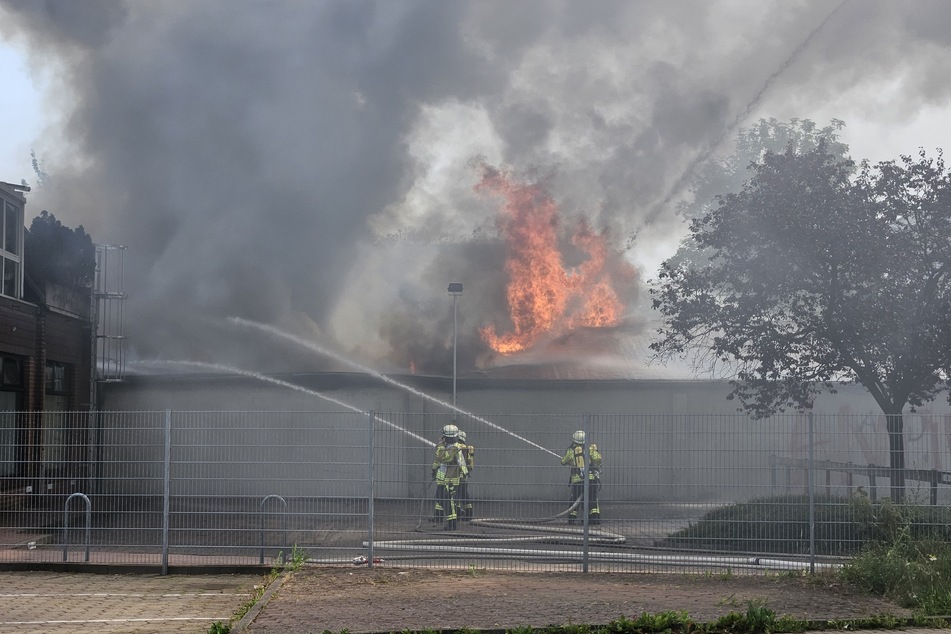 Feuerwehrleute löschen das brennende Gebäude.