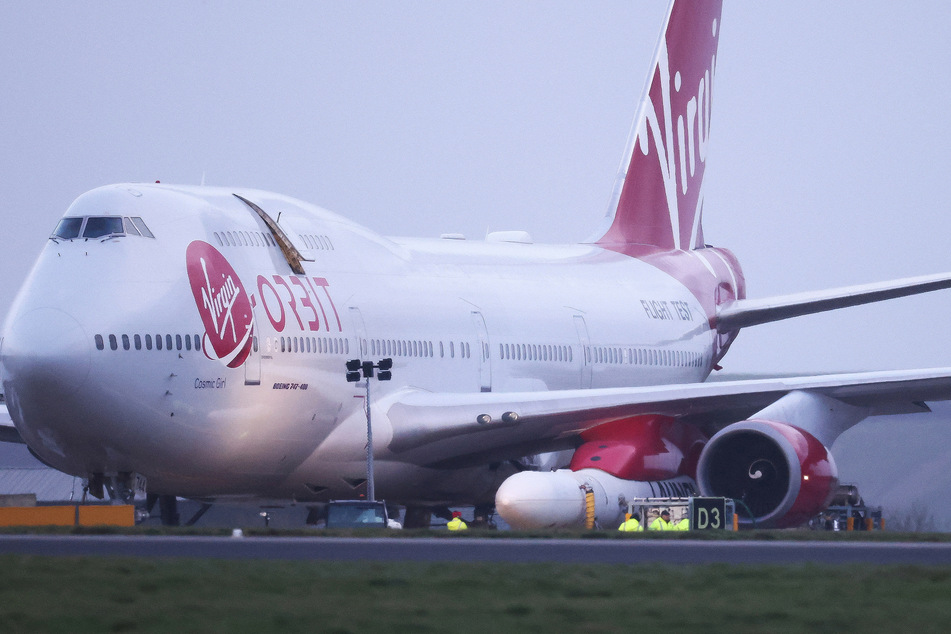 Cosmic Girl, a Virgin Boeing 747-400 aircraft, sits on the tarmac with Virgin Orbit's LauncherOne rocket attached to the wing.