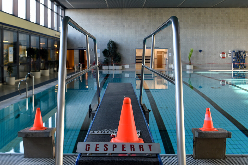 Ein Sprungbrett mit Warnkegeln und einem Schild mit der Aufschrift "Gesperrt" vor dem leeren Becken im Stadtbad Lankwitz. Die Schwimmbäder sind für den November aufgrund des Lockdowns geschlossen.