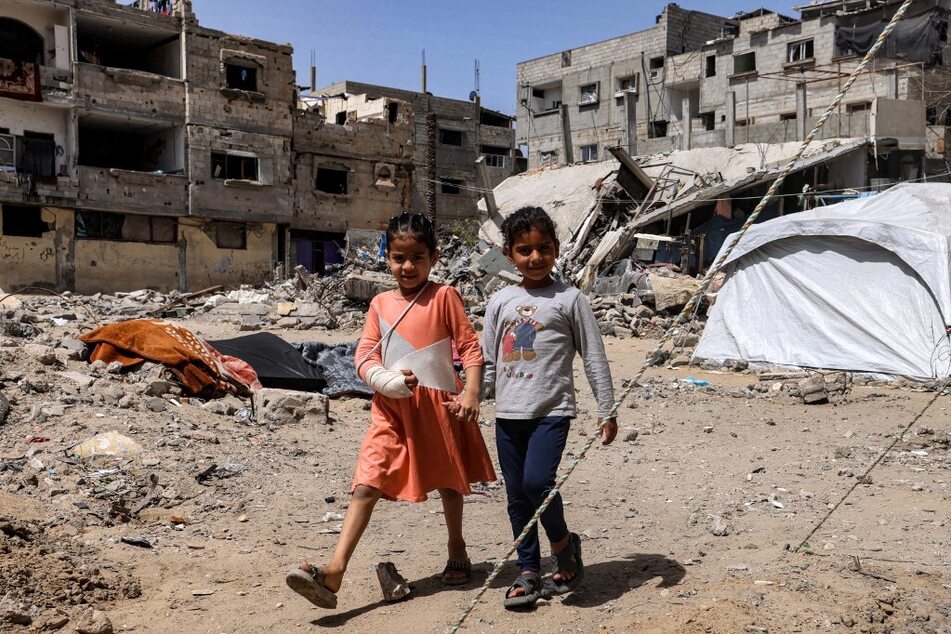 Two Palestinian girls walk past tents pitched by the rubble of destroyed buildings in Rafah in the southern Gaza Strip.