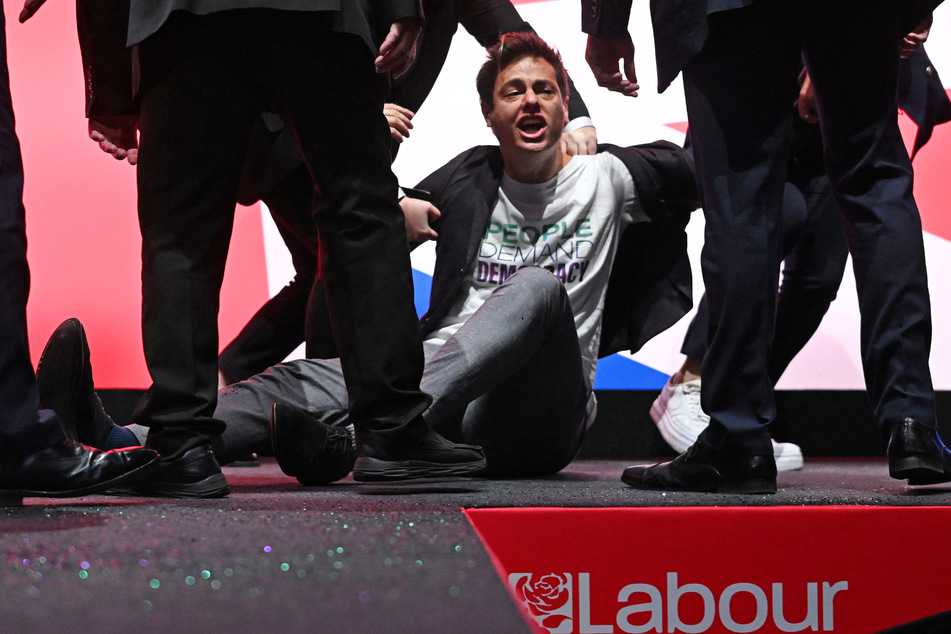Auch nachdem der 28-jährige Aktivist zu Boden gebracht wurde, rief er noch seine Parolen in Richtung der Mitglieder der Labour-Partei.