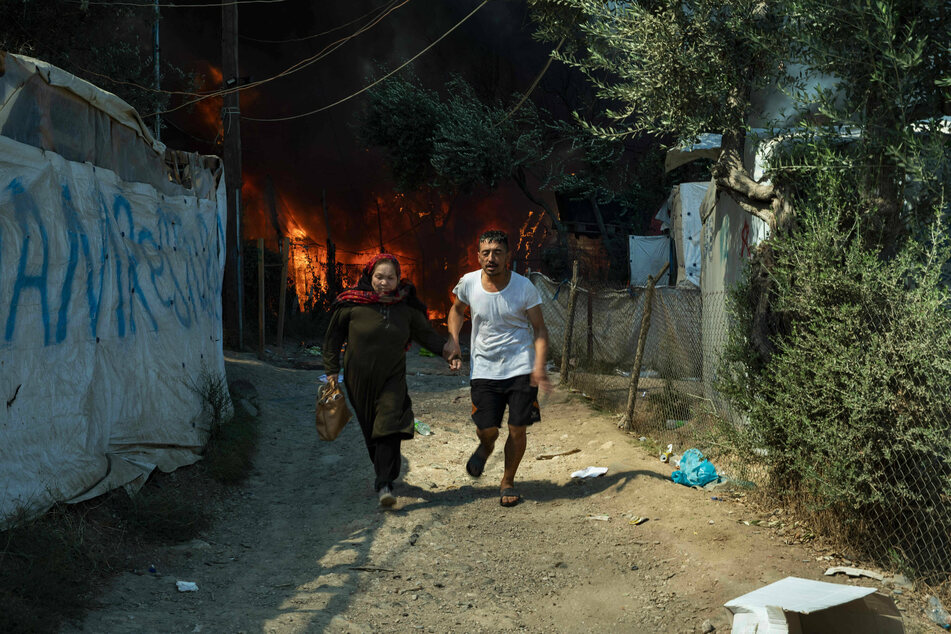 Refugees flee with their belongings from new fires in Moria camp.