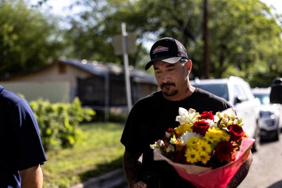 A man is shown leaving flowers at Robb Elementary School after a mass shooting, where 21 people were killed, including 19 children.