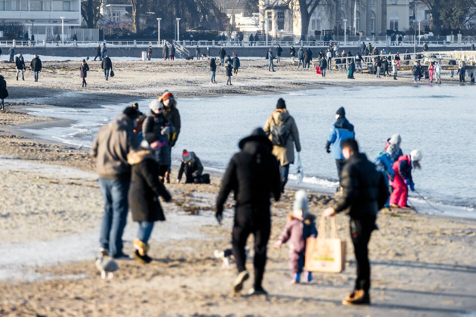 Besucher genießen einen Spaziergang am Strand von Travemünde.