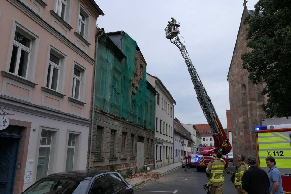 Kameraden der Feuerwehr Grimma sichern das Dach des leerstehenden Hauses.