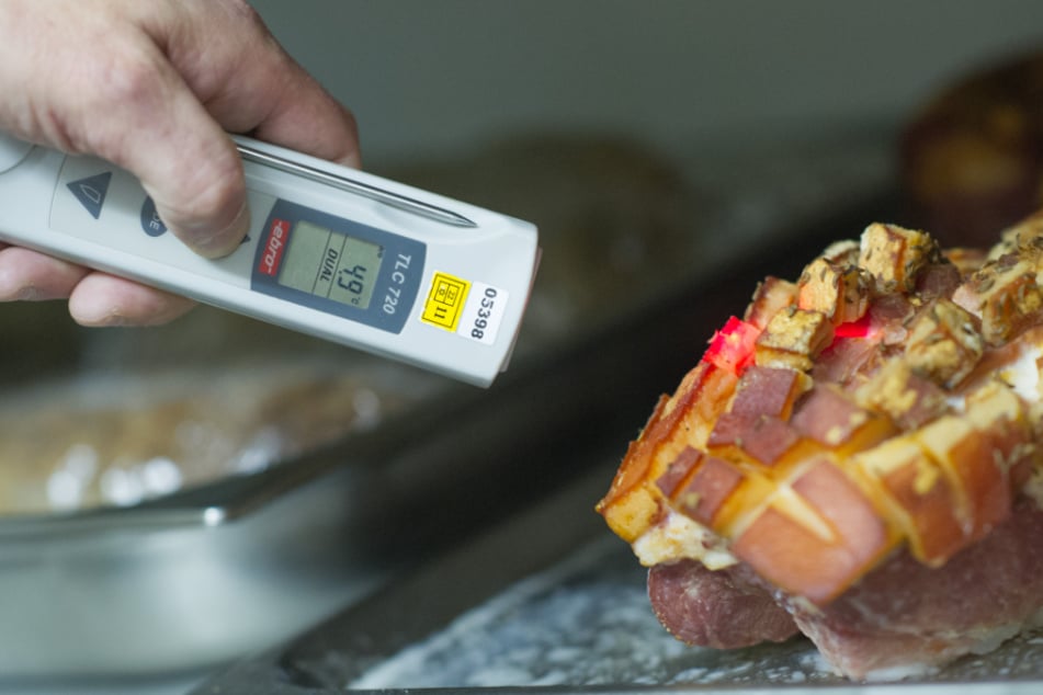 Ein Lebensmittelkontrolleur überprüft bei einer Betriebskontrolle die Temperatur einer Fleischware.