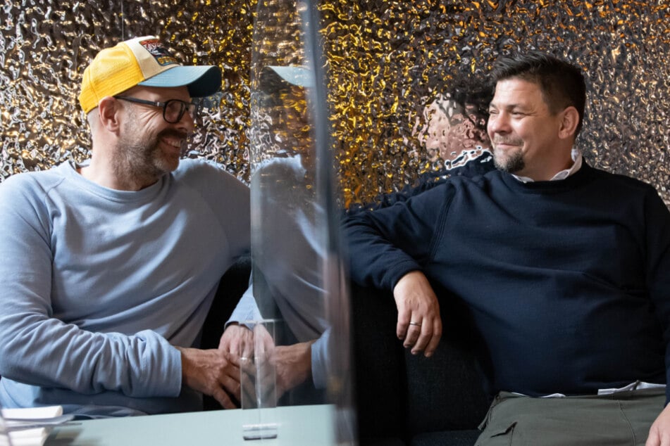 TV-Koch Tim Mälzer (r.) und Patrick Rüther sitzen an einem Tisch in der Bullerei.