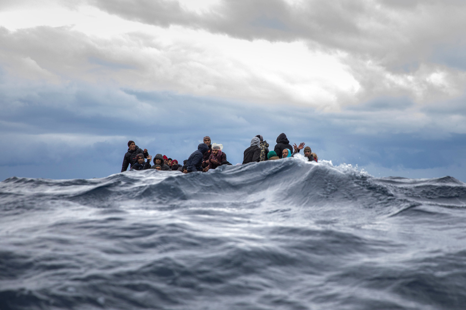 Männer aus Marokko und Bangladesch sitzen in einem überfüllten Holzboot im Mittelmeer vor der Küste von Libyen. (Archivbild)