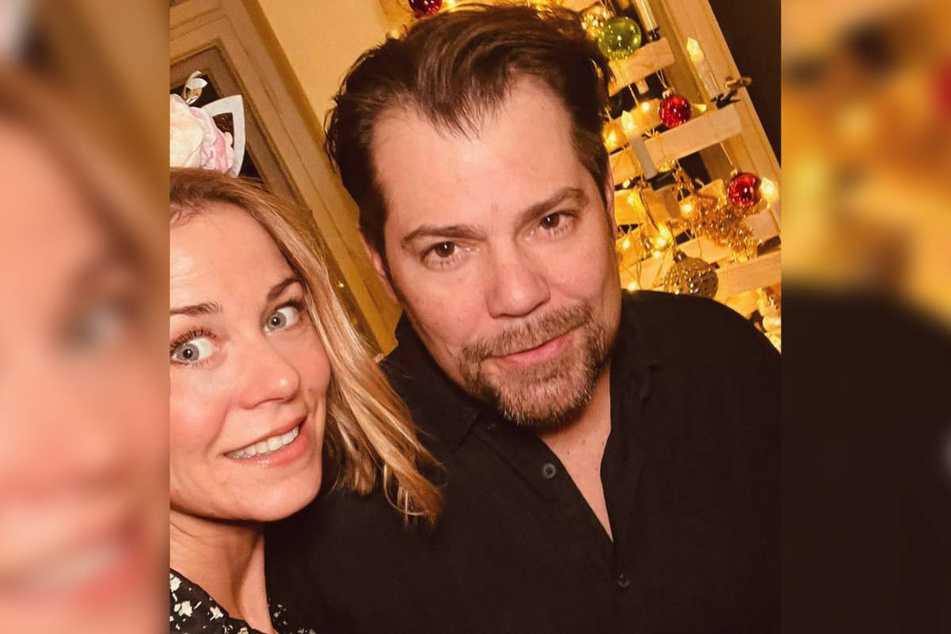 Jessica Ginkel (42) und Daniel Fehlow (47) posieren vor seinem selbst gebauten Weihnachtsbaum aus Holz.