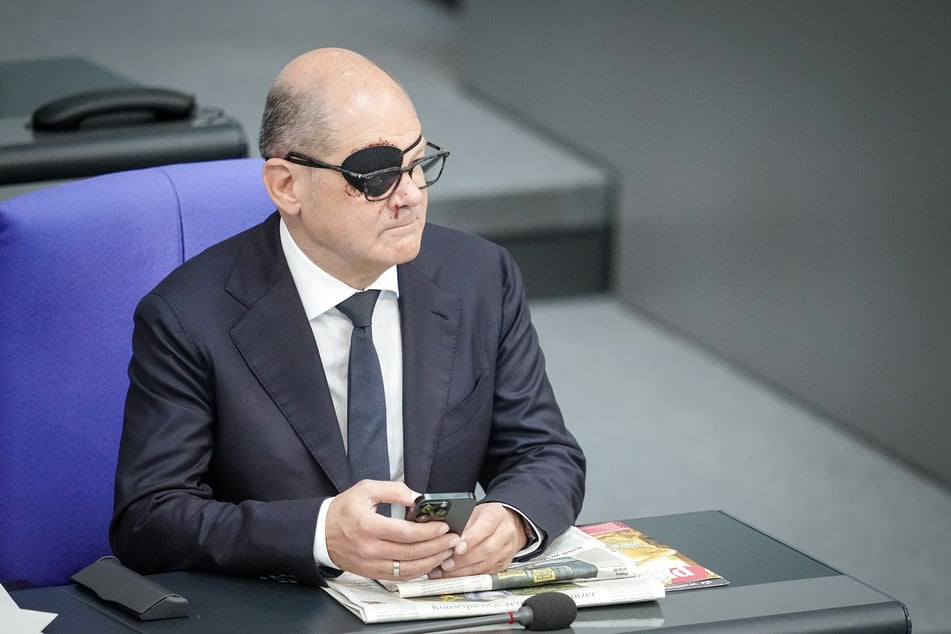 Bundeskanzler Olaf Scholz (65, SPD) mit Augenklappe und Smartphone.