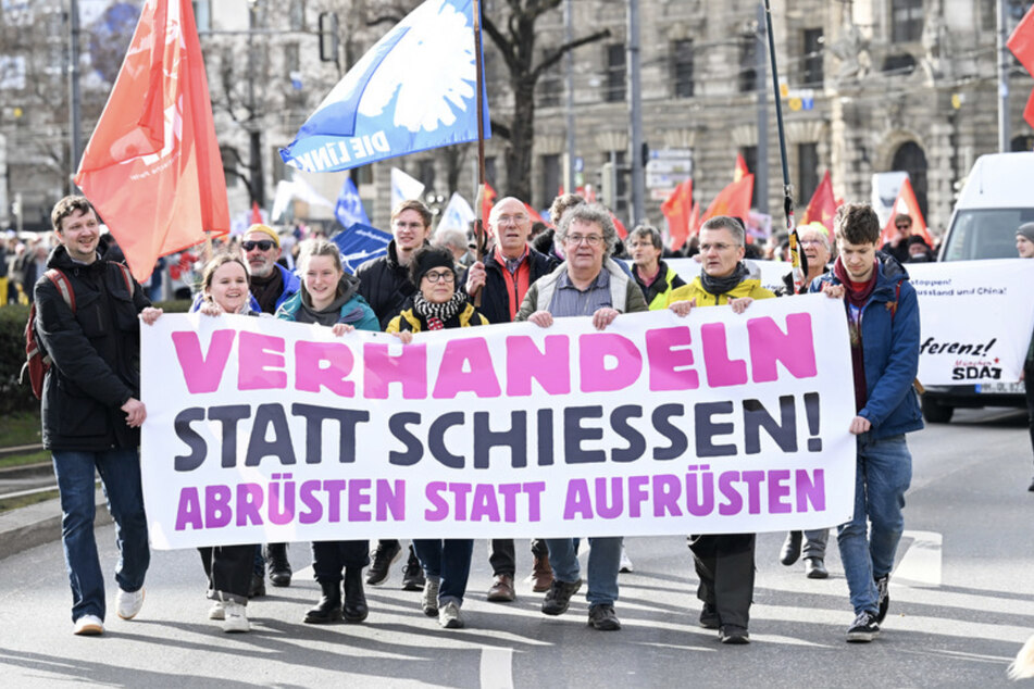 Demonstranten gegen die Münchner Sicherheitskonferenz ziehen durch die Münchner Innenstadt und tragen ein Trasparent mit der Aufschrift "Verhandeln statt schiessen! Abrüsten statt Aufrüsten".