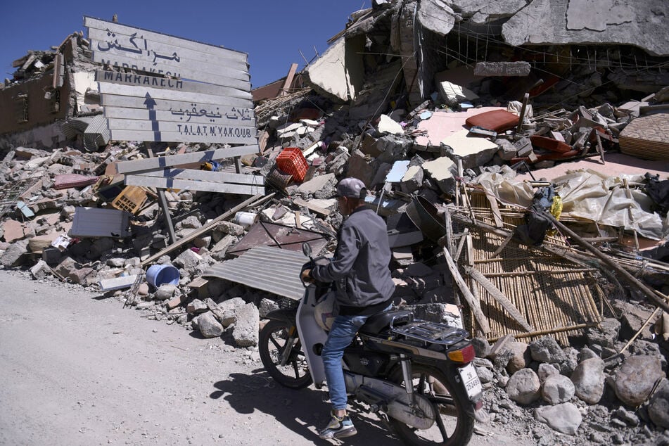 Ein Mann fährt an Trümmern von Talat N'yakoub vorbei.