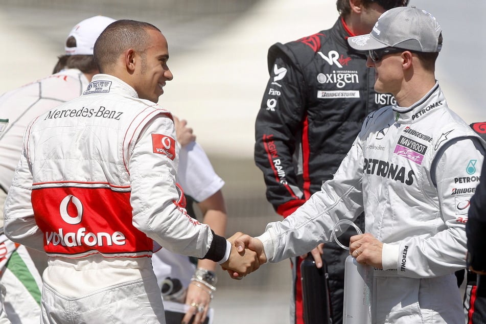 Michael Schumacher (r./57) mit dem britischen Formel-1-Piloten Lewis Hamilton (40) auf dem Bahrain International Circuit in Sakhir im Jahr 2010. (Archivbild)