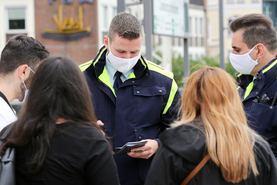 Mitarbeiter der Hochbahn-Wache kontrollieren die Einhaltung der Maskenpflicht bei einer Fahrgastgruppe.