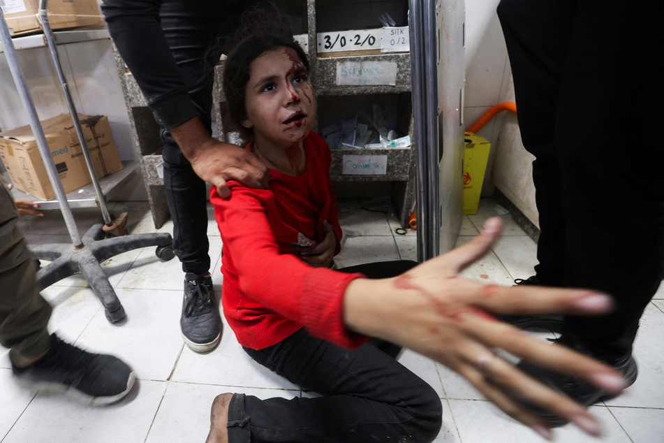 A Palestinian girl sits on the floor after she was rushed to the hospital following an Israeli strike at Nasser hospital in Khan Younis on December 3, 2023.