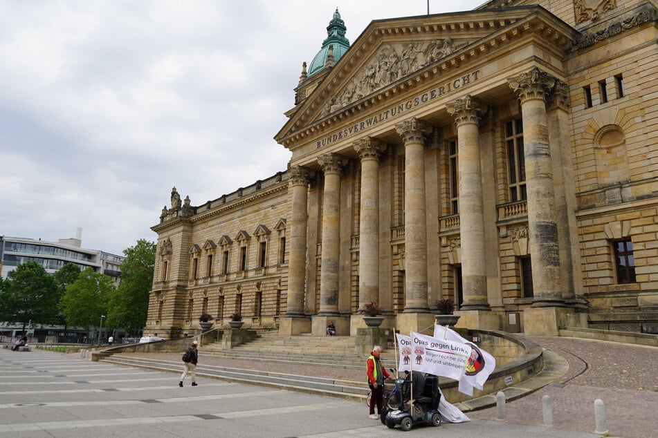 Auch am Mittag hält ein älterer Mann die Stellung und drückt seinen Protest mit zahlreichen Fahnen aus. Auf ihnen steht "Opas gegen Links".