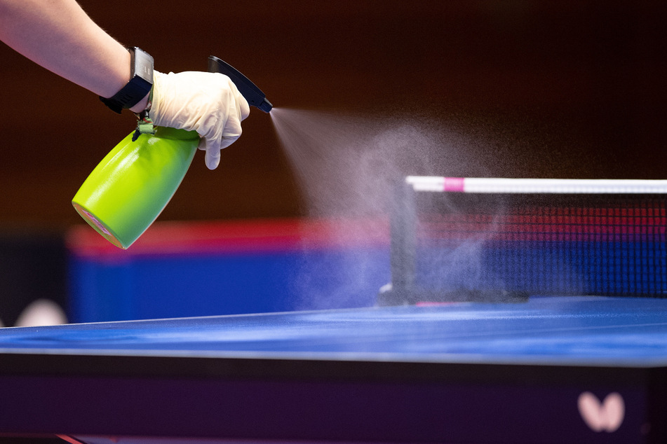 Ein Helfer desinfiziert nach einer Partie beim "Düsseldorf Masters" Halbfinale die Tischtennisplatte.