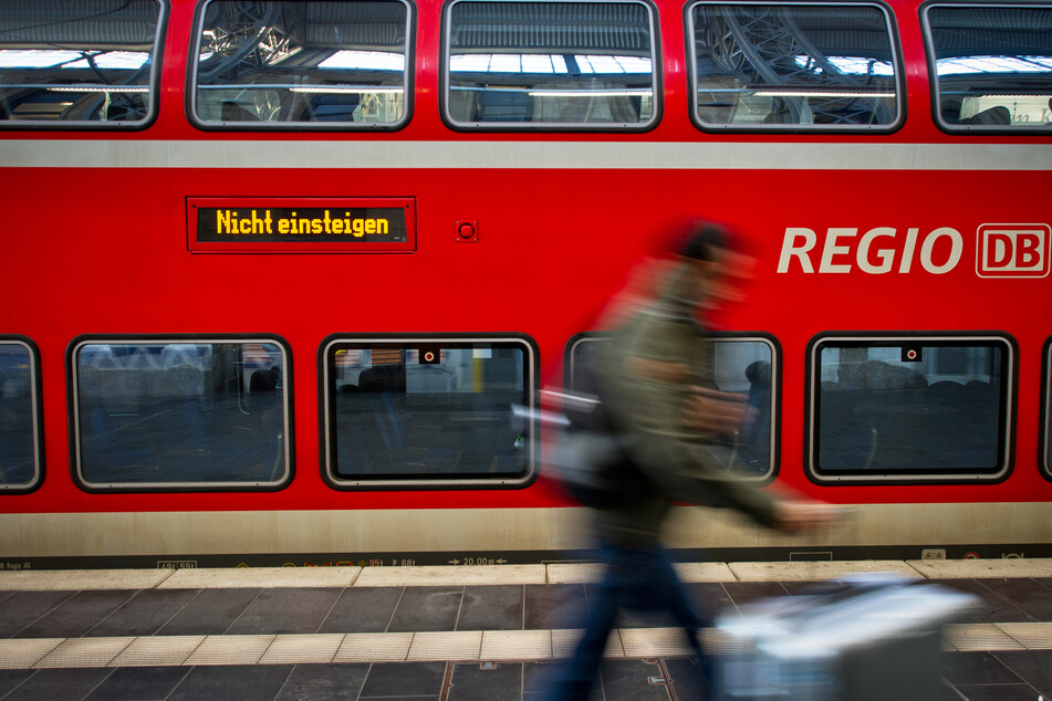 Ein Fahrgast läuft an einer Regionalbahn vorbei.