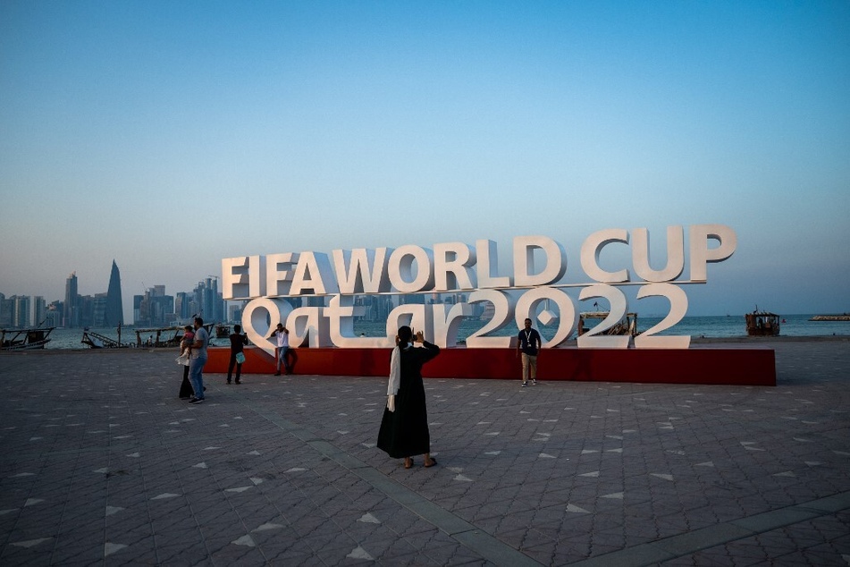 Visitors take photos with a FIFA World Cup sign in Doha on October 23, 2022, ahead of the Qatar 2022 FIFA World Cup soccer tournament.