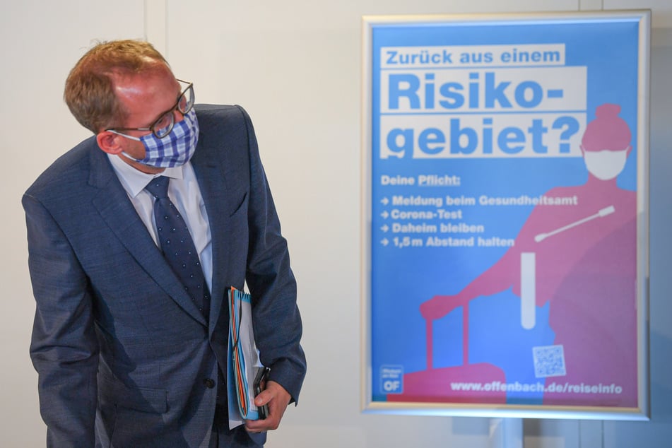 Kai Klose (Bündnis 90/Die Grünen), Sozialminister des Landes Hessen, steht zu Beginn einer Pressekonferenz im Offenbacher Stadion neben einem Plakat mit der Aufschrift "Zurück aus einem Risikogebiet?"