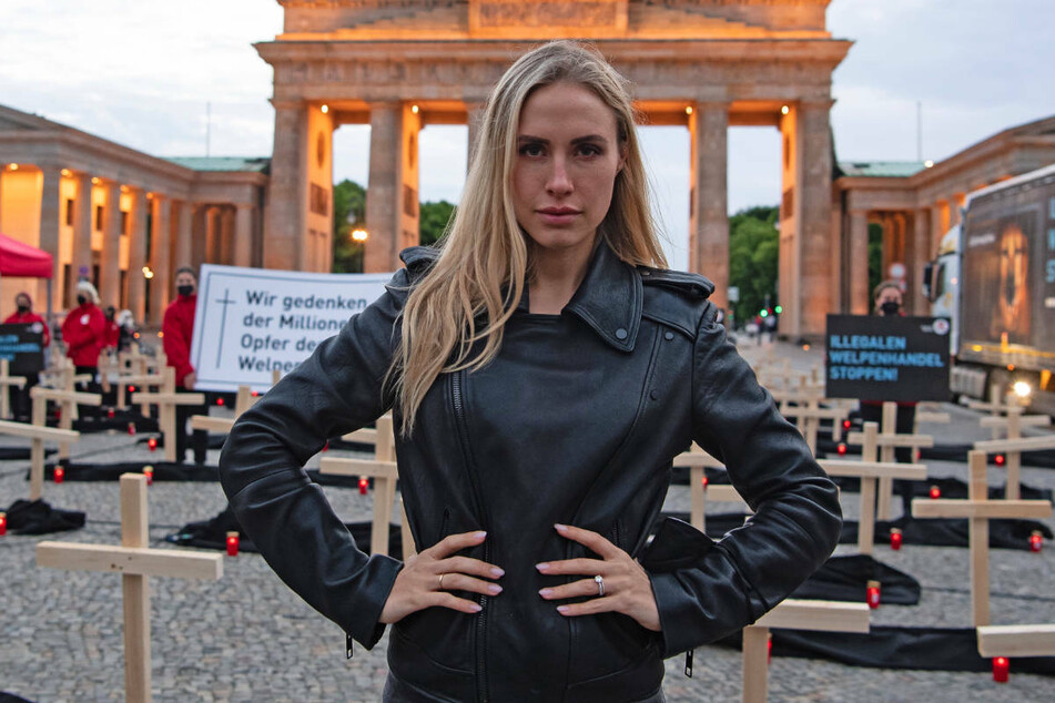 Model Alena Gerber (31) steht bei einer Mahnwache gegen den illegalen Welpenhandel vor zahlreichen Holzkreuzen und Grablichtern auf dem Pariser Platz vor dem Brandenburger Tor.