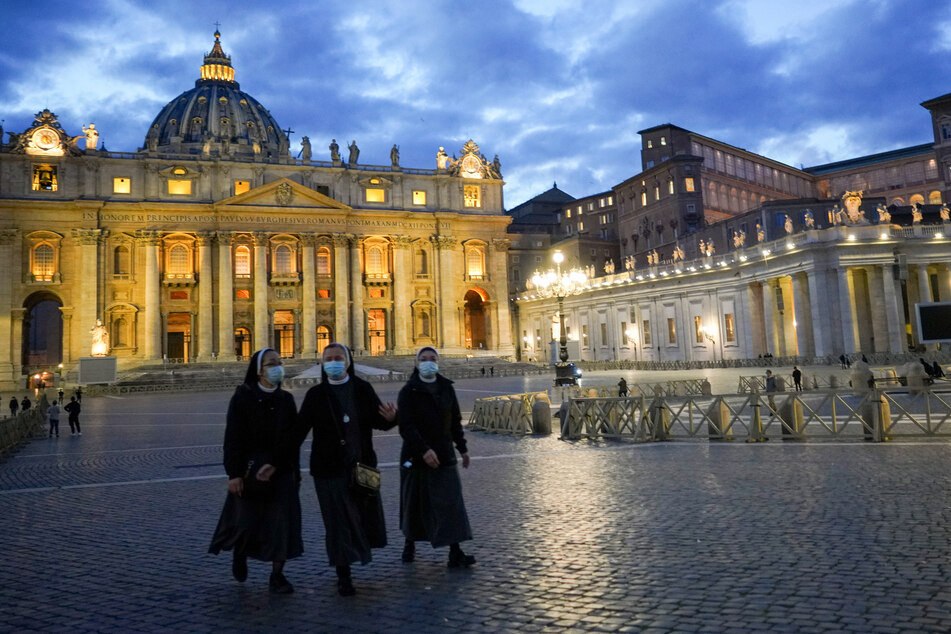 Nonnen mit Mund-Nasen-Bedeckungen gehen über den leeren Petersplatz.