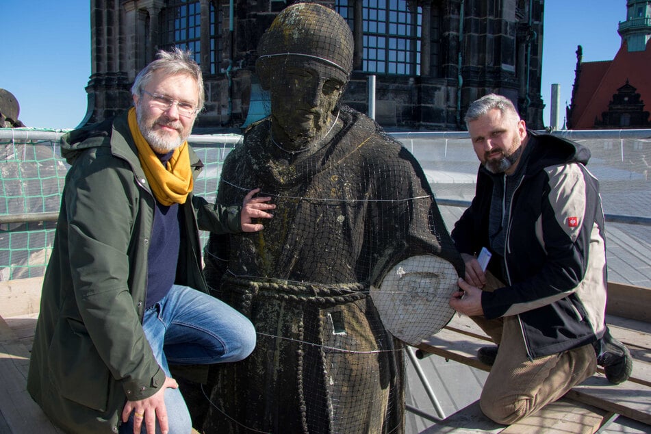 SIB-Sachgebietsleiter Kai-Uwe Beger (l.) und Restaurator Andreas Hain an der beschädigten Skulptur von Franz von Aissisi auf dem Dach der Dresdner Hofkirche.
