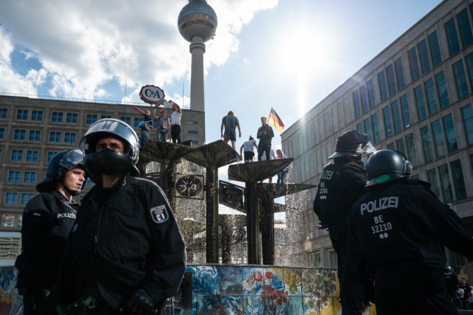 Menschen sind bei einer Demonstration auf dem Alexanderplatz auf den Springbrunnen "Brunnen der Völkerfreundschaft" geklettert.