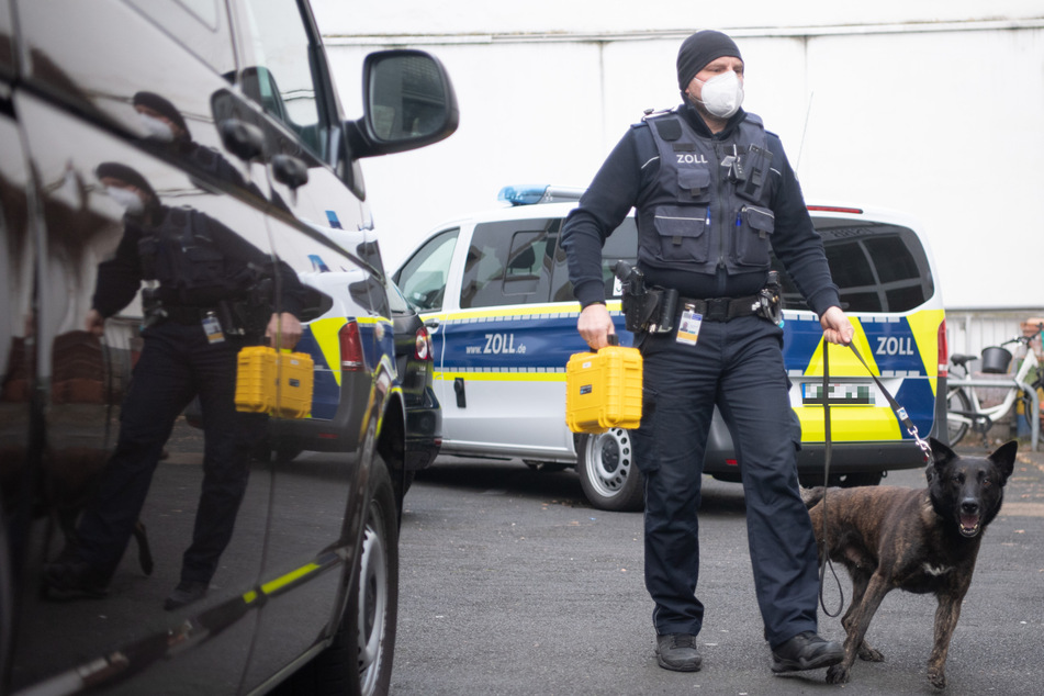 Ein Hundeführer des Zolls geht im Rahmen einer Razzia gegen Schwarzarbeit mit einem Drogenspürhund in ein Bürogebäude in Frankfurt.